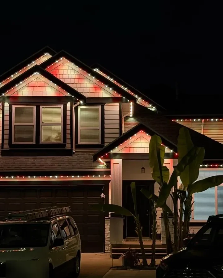 Permanent RGBWW roofline lights glowing along the eaves of a house at night